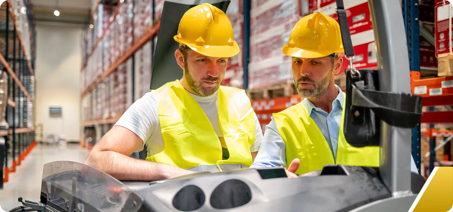 Two warehouse workers talking wearing safety equipment